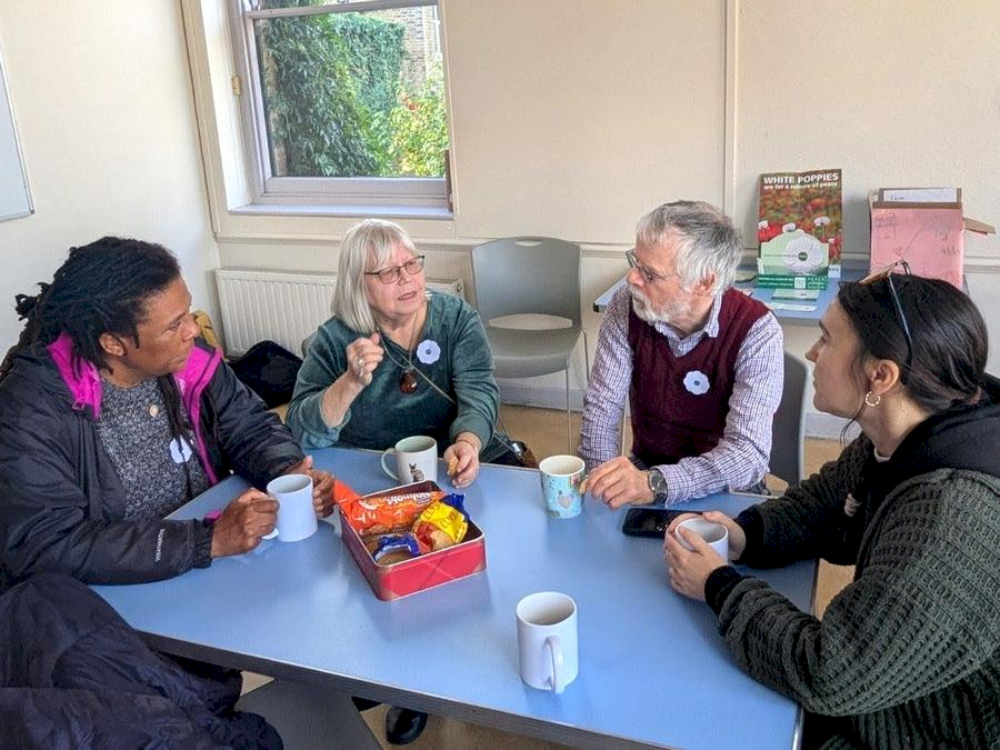 four people sitting around a table with tea and biscuits